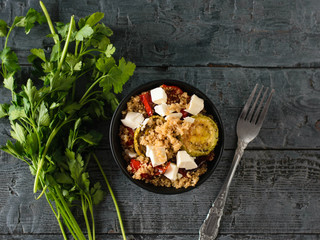 Beautiful salad of baked vegetables, quinoa and cheese on a black table. Vegetarian dish. The view from the top. Flat lay.