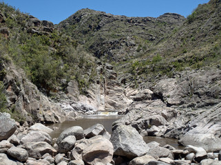View of the Yuspe river running through the mountains at Cerro Blanco reserve, near Tanti and Los Gigantes, Cordoba, Argentina