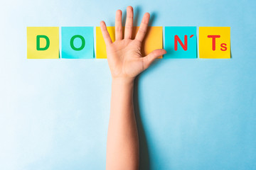 Do's and don'ts sign with multicolored sticky notes and a palm of hand showing 5 fingers on blue background