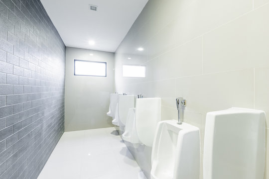 public toilet urinals lined up, no privacy.