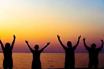 Fototapeta premium A group of women rise hands up to sky freedom concept with blue sky and beach sunset.