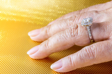 Beautiful and luxury wedding diamond ring worn on woman hand on gold background