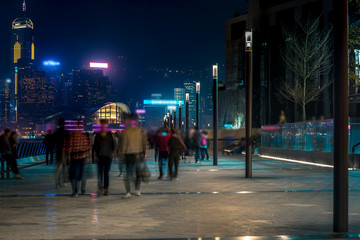 Hong Kong cityscape at night. Tourists walking on the waterfront