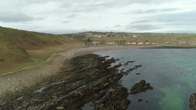 Rising aerial view across the rocky coastal area and sea heading towards Dunbeath, Caithness, Scotland