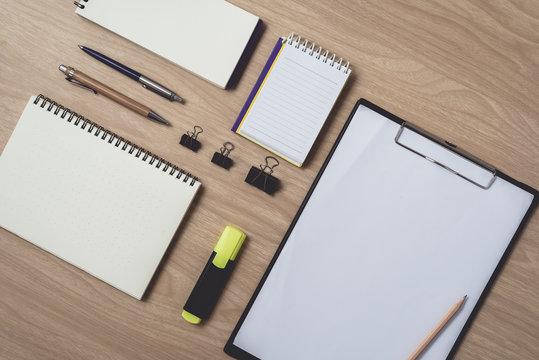 Workspace with diary or notebook and pen, pencil, hightlight pen, metal clip on wooden background