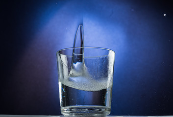 Falling and jumping glass with spilling liquid on a blue gradient background