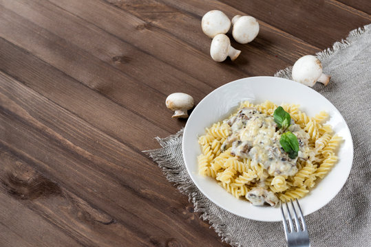 pasta with mushroom sauce and cheese on a wooden background, Basil