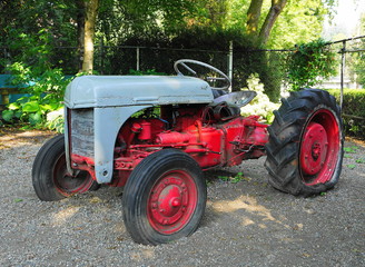 Very old red farm tractor in the field close up.
