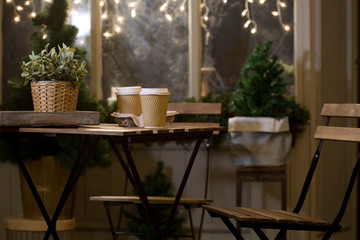 Winter. Street cafes. City, street, romantic date. Two cups of coffee, with a coffee. Coffee in a paper Cup. Wooden furniture in the cafe. Bench, vintage cafe.
