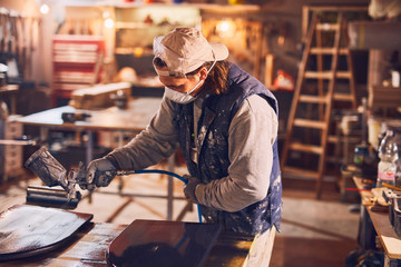 Fototapeta na wymiar Male carpenter working on old wood in a retro vintage workshop.