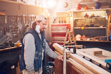 Male carpenter working on old wood in a retro vintage workshop.