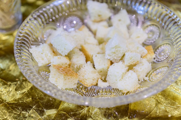 chopped crispy bread in crystal plate on golden background. Fast snack, selective focus.