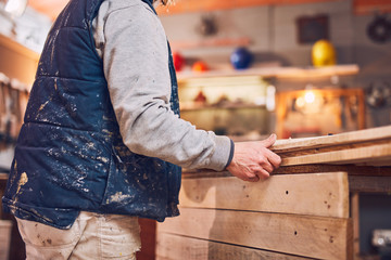 Male carpenter working on old wood in a retro vintage workshop.