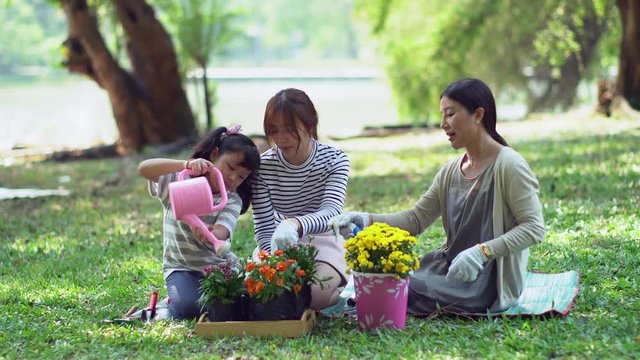 Cute youngest daughter planting flowers with mother and oldest sister