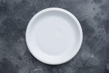 Disposable plastic tableware plates on dark background with copy space.