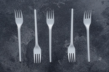 Disposable plastic tableware plugs on dark background with copy space.