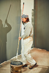 Painter painting walls with a extender roller indoors.