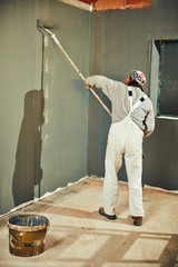 Painter painting walls with a extender roller indoors.
