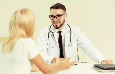 Male doctor is talking to female patient in hospital office. Healthcare and medical service.