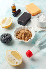 set of eco-friendly natural cleaning products on wooden kitchen table: mustard, soda, essential oils, cellulose sponge, rags, lemon, metal brush, rubber gloves, soap