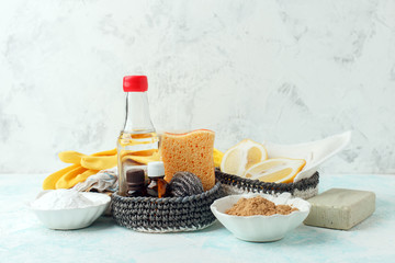 set of eco-friendly natural cleaning products on wooden kitchen table: mustard, soda, essential oils, cellulose sponge, rags, lemon, metal brush, rubber gloves, soap