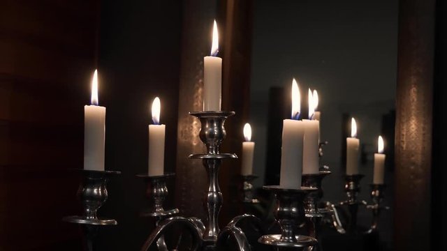 Mid Handheld Shot of a Few Candles on a Silver Candlestick with Wooden Walls and a Mirror in The Background