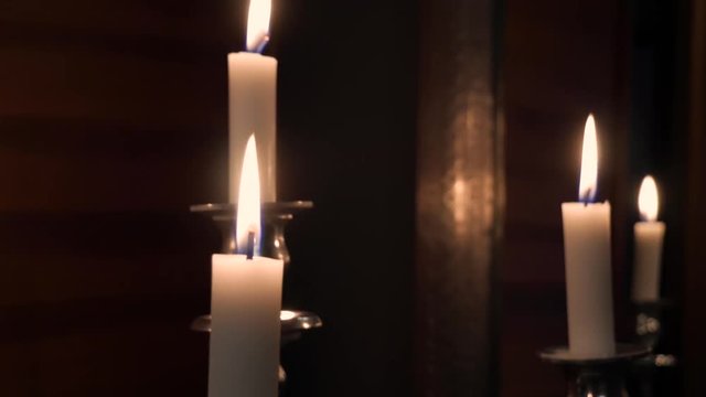 Mid Handheld Shot of a Few Candles on a Silver Candlestick with Wooden Walls and a Mirror in The Background