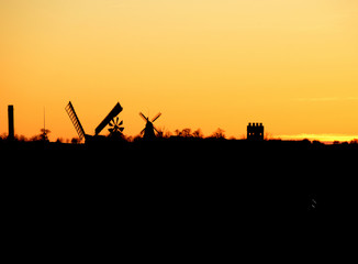 City silhouette-skyline in a yellow-orange evening light with two old windmills