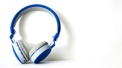 A blue headphone isolated on white background. Listening music equipment. Earphone or headset with no cable. Copy space for text. Trendy toy in digital era for music addiction. Addicted to music.