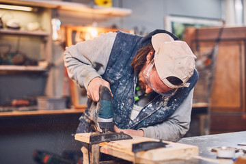 Male carpenter working on old wood in a retro vintage workshop.