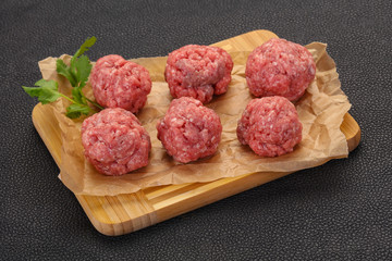 Raw meatball over wooden background