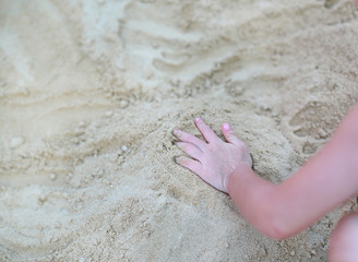 Close-up hand of little girl playing sand.