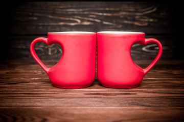 two heart shaped mugs with tea on brown background 