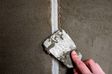 Plasterer sealing joint of building wall with putty knife. - Powered by Adobe