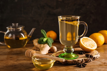 Cup of tasty drink with lemon, ginger and honey on wooden table