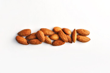 A horizontal row of dry raw almond nuts on a studio white background.