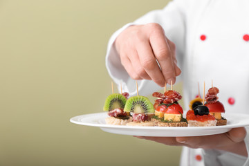 Chef holding plate with tasty canapes, closeup