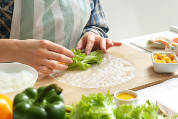 Woman preparing tasty spring rolls