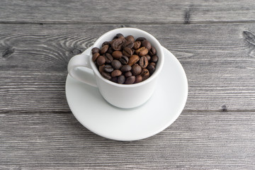 Coffee cup and coffee beans on wooden background. Top view and selective focus
