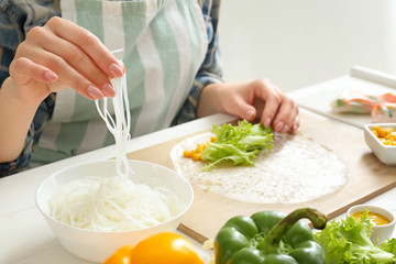 Woman preparing tasty spring rolls, closeup