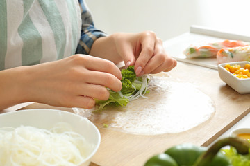 Woman preparing tasty spring rolls, closeup
