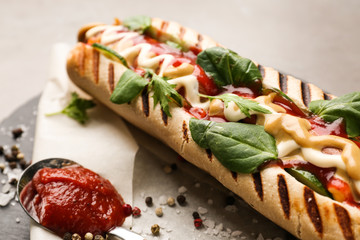 Tasty hot dog with sauce on slate plate, closeup