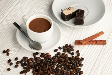 A cup of coffee with milk and coffee beans scattered on the table