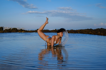 A stunning yoga instructor stretching and posing by the beach