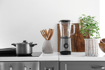 Set of utensils and blender in kitchen