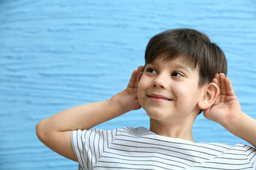 Little boy with hearing problem on color background