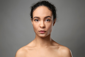 Portrait of beautiful African-American woman on grey background
