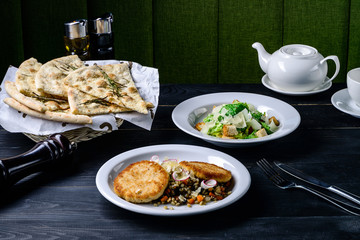 dinner set lunch in a cafe, meat and caesar salad on black table