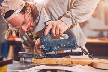 Male carpenter working on old wood in a retro vintage workshop.