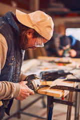 Male carpenter working on old wood in a retro vintage workshop.